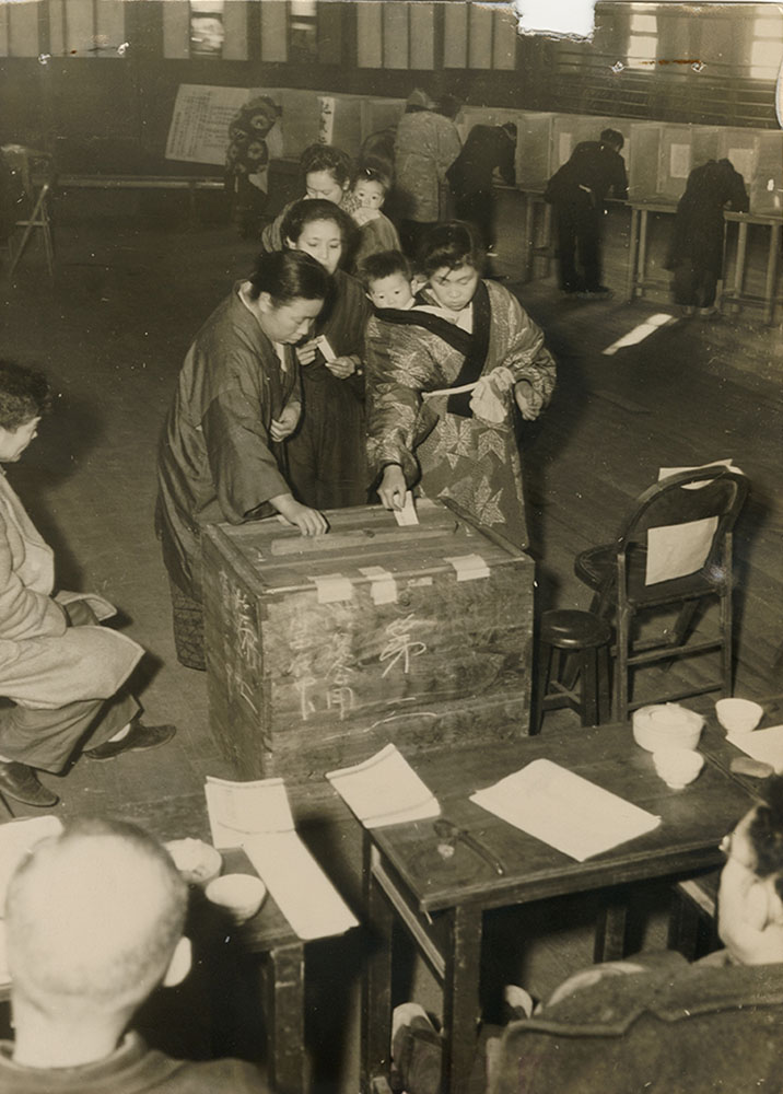Image of women in Japan voting while carrying children on their backs