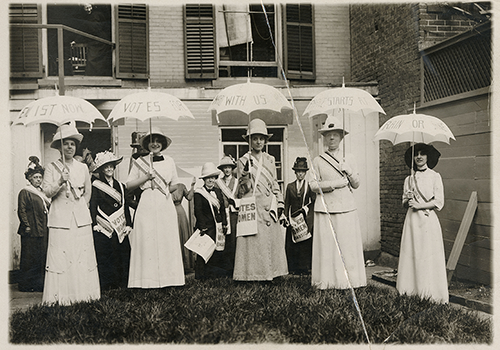 Photo of suffragists in white dresses with parisols