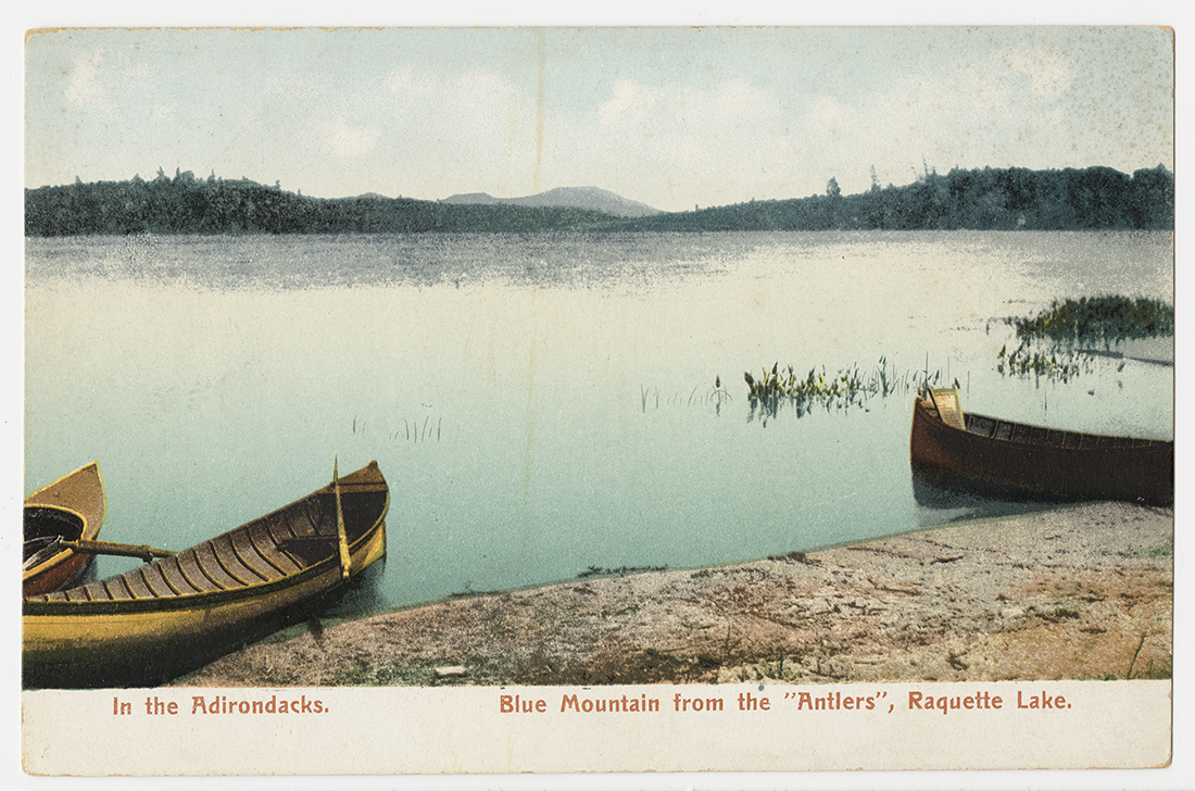 'In the Adirondacks, Blue Mountain from the "Antlers" Raquette Lake.' postcard with image of two canoes on the shore of a lake.