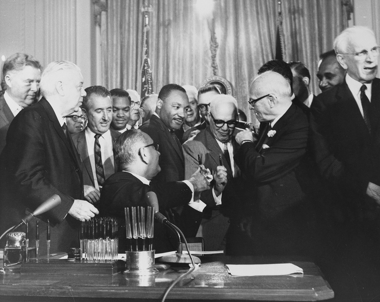 President Lyndon Johnson handing pens to Dr. Martin Luther King, Jr. and AFL-CIO President, George Meany, at the signing the 1964 Civil Rights Act