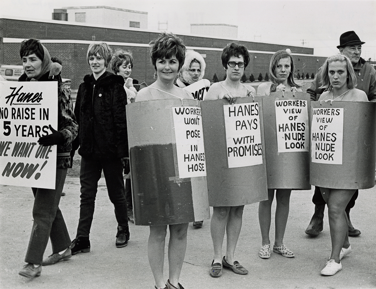 Picketing strikers protest low wages and the gendered irony of their employer’s “Nude Look” advertising brand of hosiery, Textile Workers Union of America