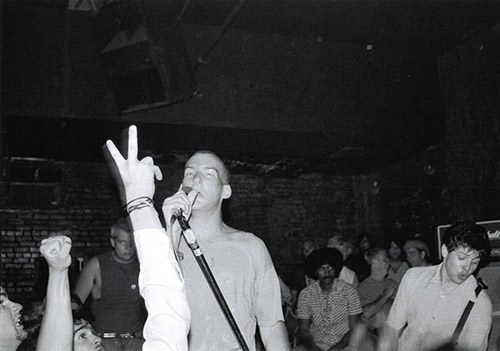 Lyle, Ian and Henry, 1982. A close-up of a band performing, surrounded by a crowd of people.