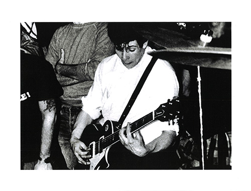 Lyle, Ian and Henry, 1982. A close-up of a band performing, surrounded by a crowd of people.