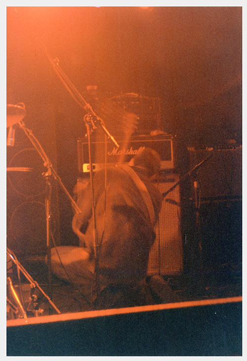 A photograph of Marc Nelson on his knees onstage moves his guitar through the air with his back to the audience.